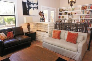 A living room with a fireplace, a bookshelf, and a dining area with chairs.