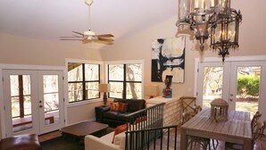 Un salón espacioso con ventilador de techo, chimenea y una mesa de comedor.