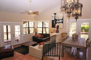 A spacious living area with a ceiling fan, a fireplace, and a dining table.