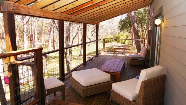 Un espacio de estar al aire libre techado con muebles de mimbre y una terraza de madera.