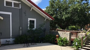 Un immeuble résidentiel avec une allée en gravier, un espace extérieur aménagé pour s’asseoir et un mur en pierre.