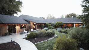 A two-story house with a covered patio, outdoor seating, and landscaped garden.