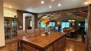 A spacious kitchen with a large island, wooden cabinets, and a brick wall.