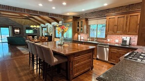 A spacious kitchen with wooden cabinets, a central island, and a dining area with chairs.