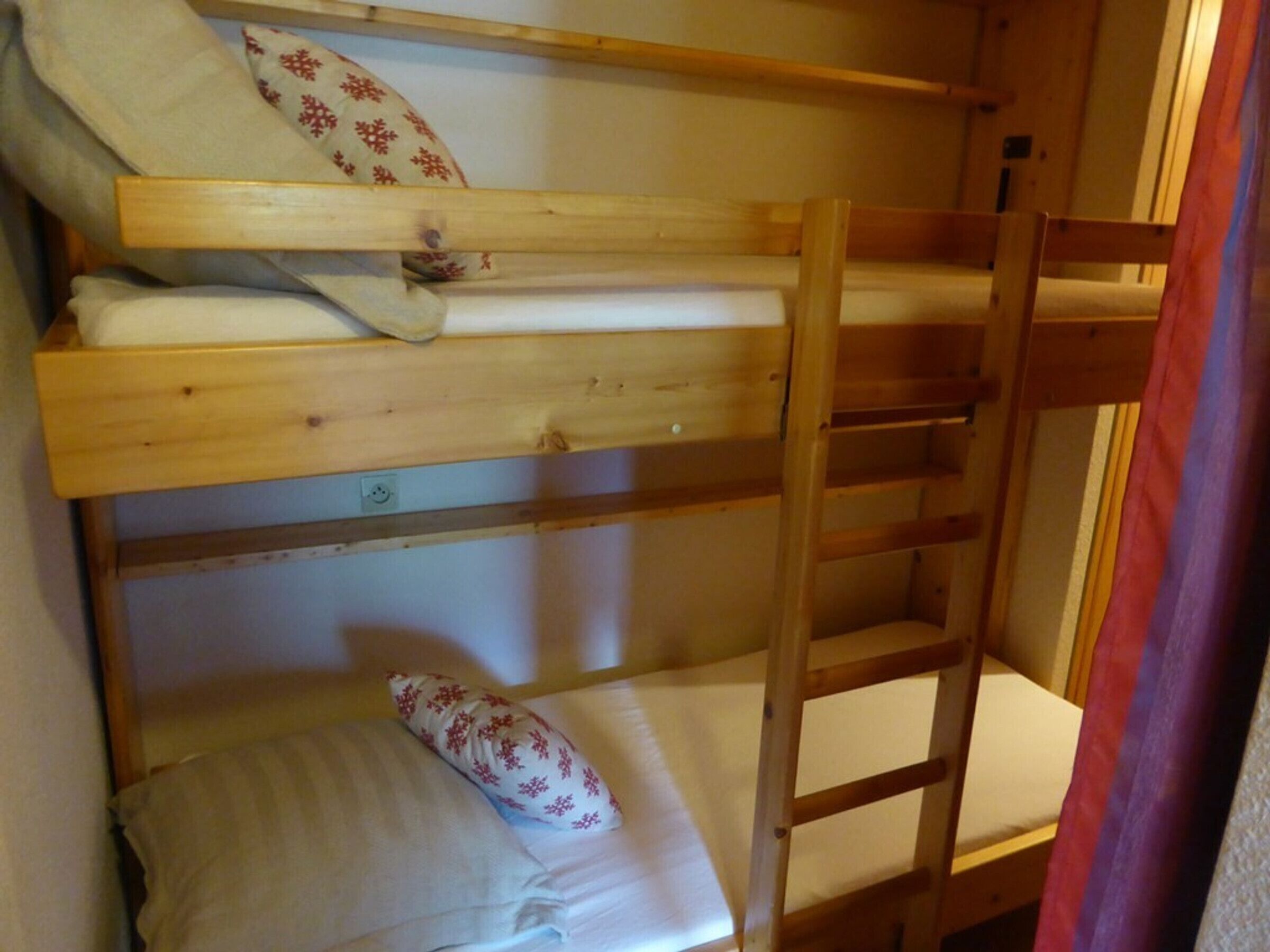 Ein Stockbett mit zwei Ebenen, jeweils mit Kissen und Decke.