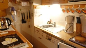 Een keuken met houten kasten, een koffiezetapparaat, een spoelbak en een fornuis.