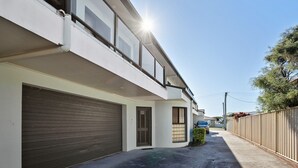 A modern two-story residential building with a garage, a covered driveway, and a fenced yard. - 3-45 Park Street - Spacious Townhouse (EVANS HEAD)