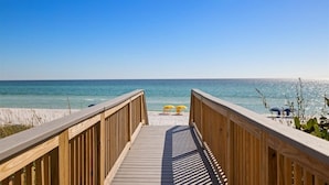 A wooden boardwalk leading to a beach with two yellow umbrellas. - Private Beach, 5 BR w/awesome views, private pool & golf cart (Santa Rosa Beach)