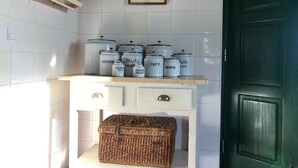Una cocina con baldosas blancas, una encimera blanca y una puerta verde. Hay varios recipientes blancos sobre la encimera, cada uno con un nombre diferente.