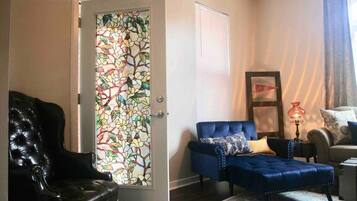 Una sala de estar con un sillón de cuero negro, un sofá tapizado azul y un alfombra estampada.