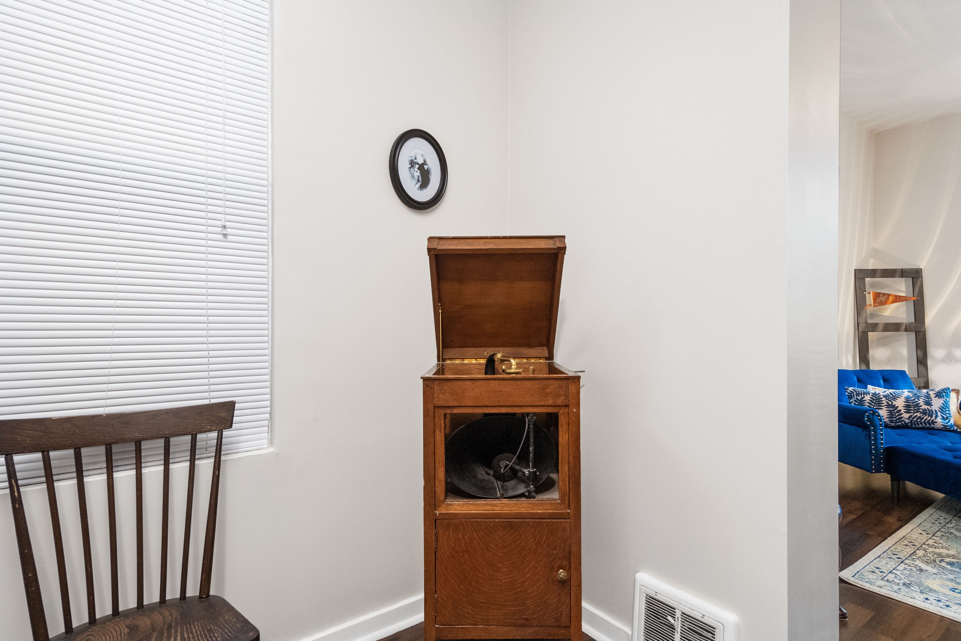 A corner room with a wooden cabinet, a chair, and a blue sofa.