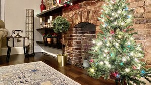 A cozy living room with a brick fireplace, a Christmas tree, and a vintage telephone. - Centrally located in the Tower Grove East neighborhood! (St. Louis)