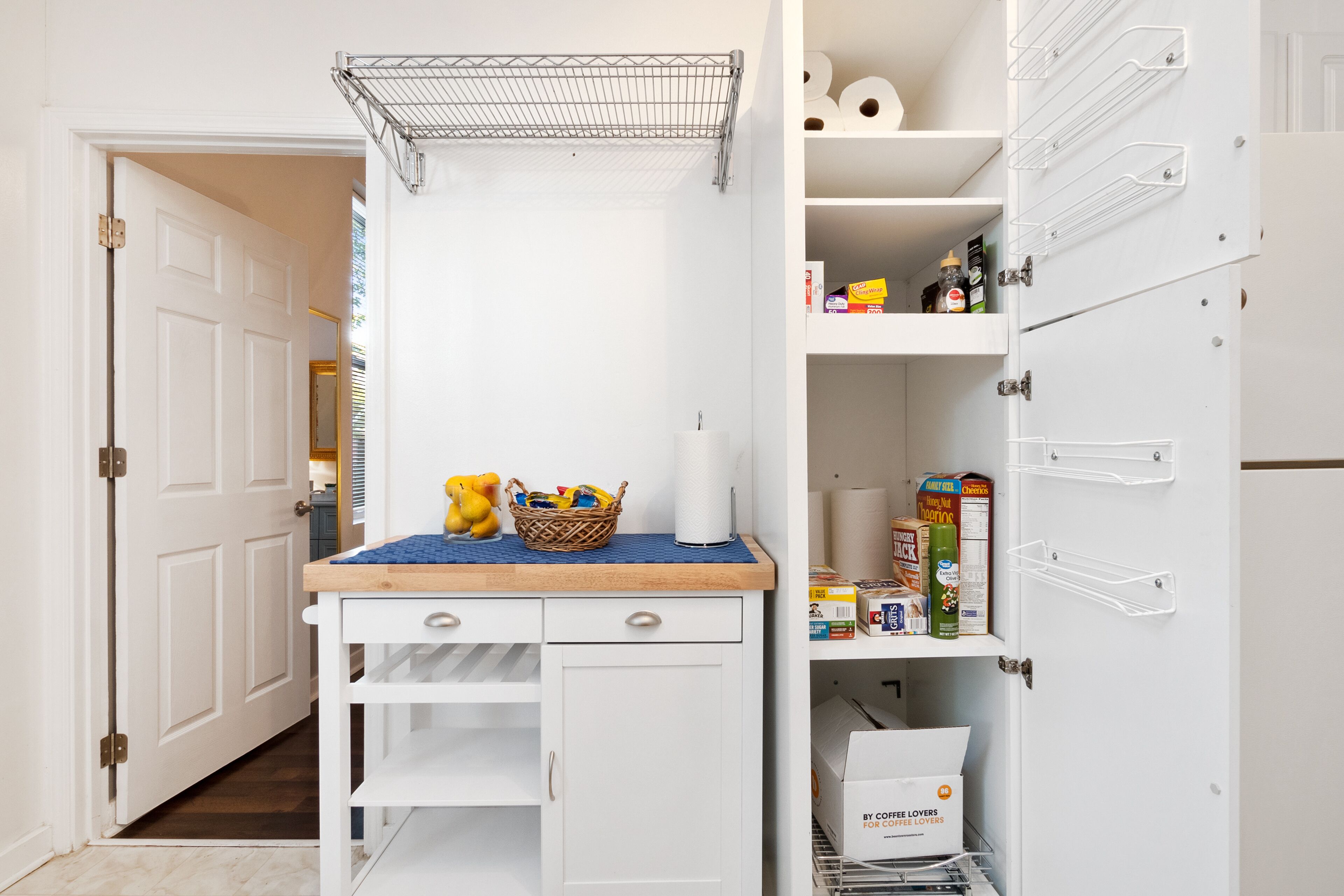 A kitchen with a white cabinet, a wooden countertop, and a metal rack above it.