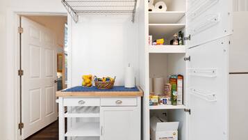 A kitchen with a white cabinet, a wooden countertop, and a metal rack above it.