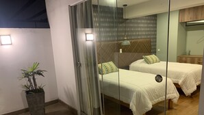 Een kamer met twee bedden, een plant in pot en een glazen schuifdeur.