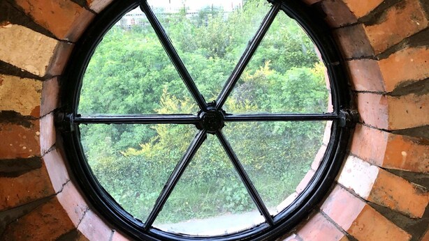 A circular window with a brick arch design, surrounded by a brick wall. - The Horse Stables (Glastonbury)