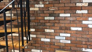 A spiral staircase with a brick wall background. - The Horse Stables (Glastonbury)