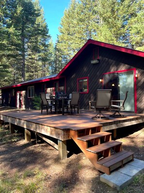A cabin with a deck, outdoor seating, and a glass door entrance.