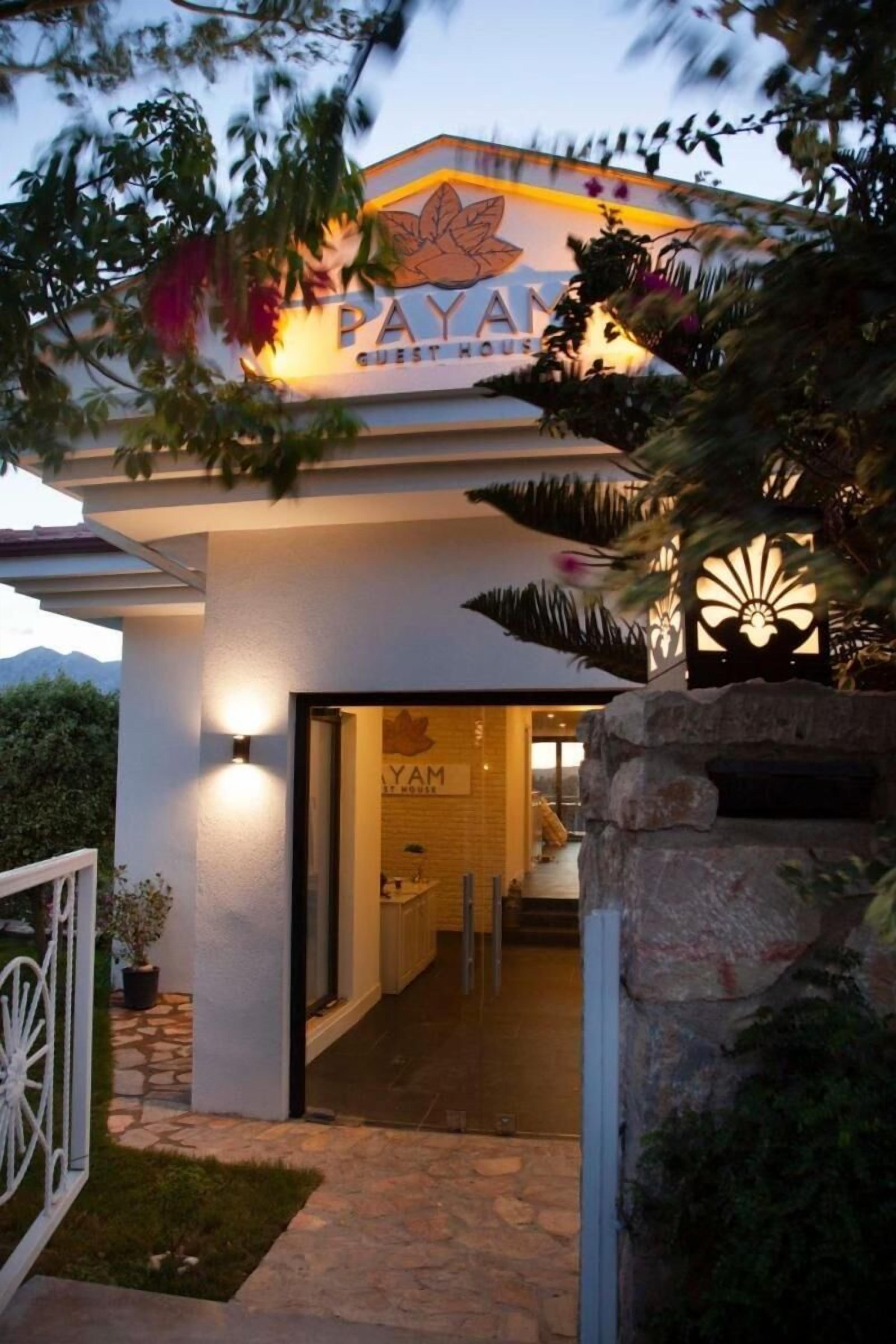 A hotel entrance with a sign reading "PAYAM GUEST HOUSE" and a pathway leading to the interior.