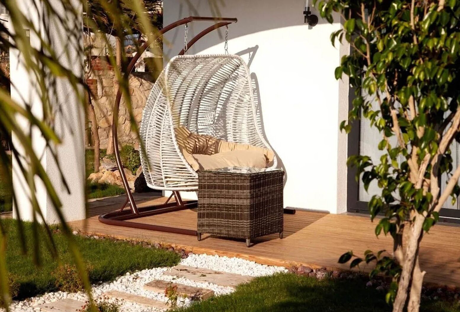 Uma cadeira de vime com almofada em um jardim.