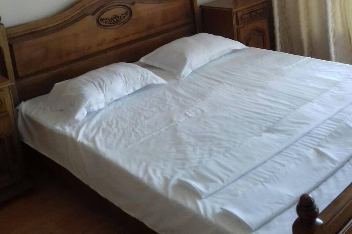 Uma cama de solteiro com cabeceira de madeira, mesa de cabeceira e criado-mudo.