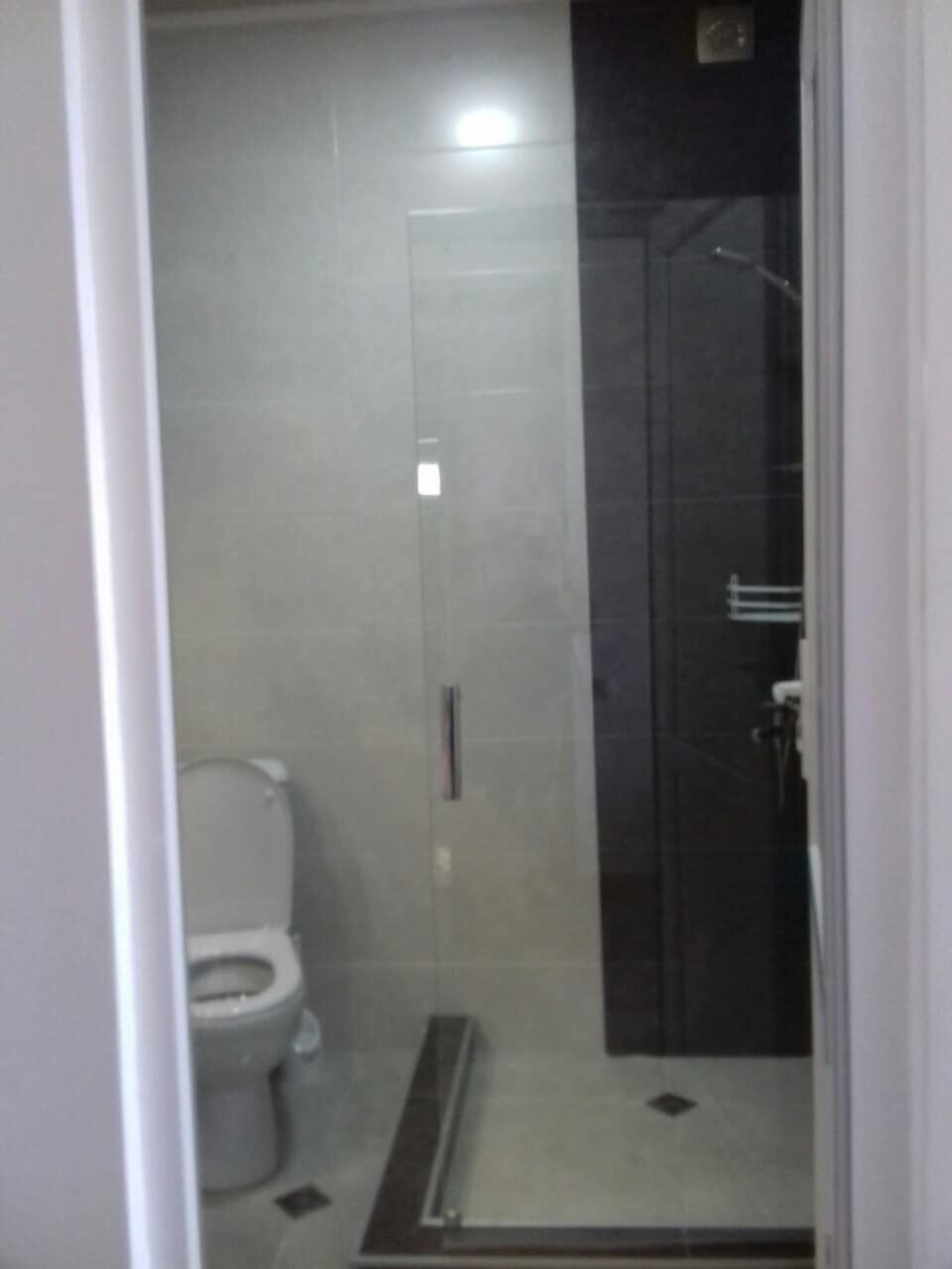 Een badkamer met toilet, douchecabine en een glazen deur.