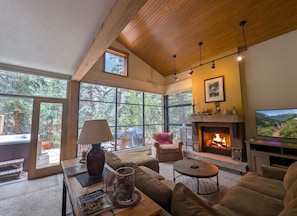 A spacious living room with a fireplace, large windows, and a cozy seating area. - Rustic & Warm Townhome with a Private Hot Tub (Keystone)