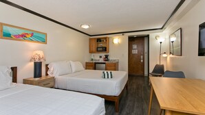 Una habitación de hotel con dos camas, un escritorio, kitchenette y baño.