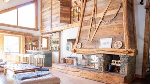 Un intérieur rustique avec des poutres apparentes, une cheminée en pierre et un coin bar.