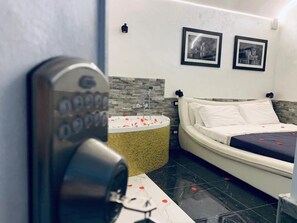 Una habitación de hotel moderna con una cama, un tocador con espejo y un dispositivo de seguridad fijado a la pared.