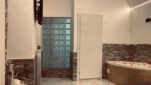 A modern bathroom with a glass shower, a bathtub with rose petals, and a marble floor. - Popolo Relax (Rome)