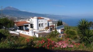Une maison située sur la côte, avec vue sur la mer et une montagne en arrière-plan.