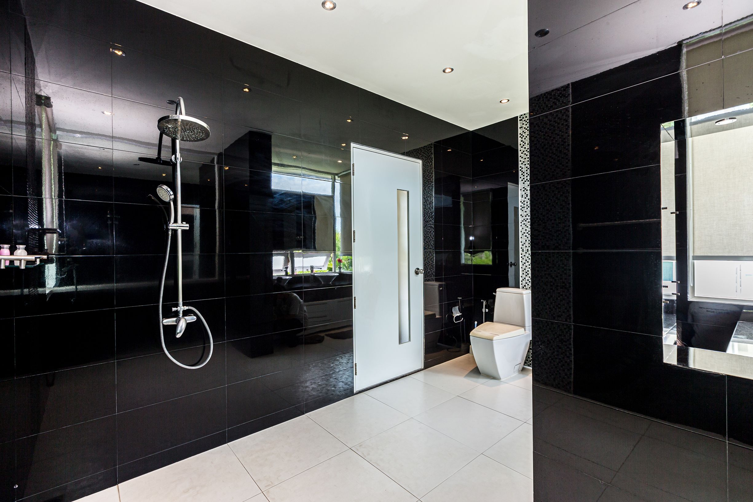 A modern bathroom with a black tiled wall, a white toilet, and a shower area.