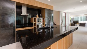 Una cocina moderna con encimera de granito negro, electrodomésticos de acero inoxidable y armarios de madera.