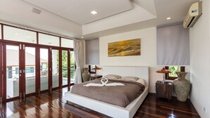 Un dormitorio amplio con una cama grande, vistas al exterior a través de puertas corredizas y un cuadro en la pared.
