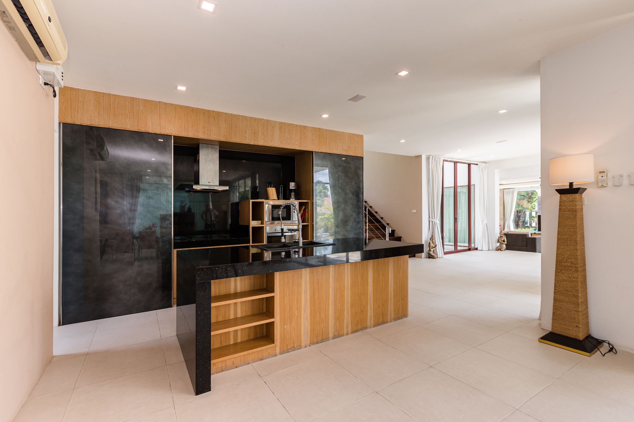 A modern kitchen with a black countertop, wooden cabinetry, and a built-in stove.