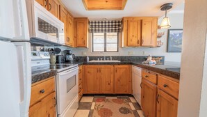 A compact kitchen with wooden cabinets, a microwave, stove, and a sink.