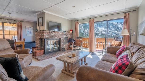 A cozy living room with a fireplace, comfortable seating, and a large window with a mountain view.