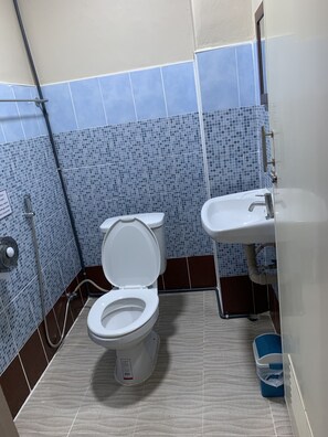 A bathroom with a white toilet, a sink, and blue-tiled walls. - Achcha - MRT Itsaraphap Station  (Bangkok)