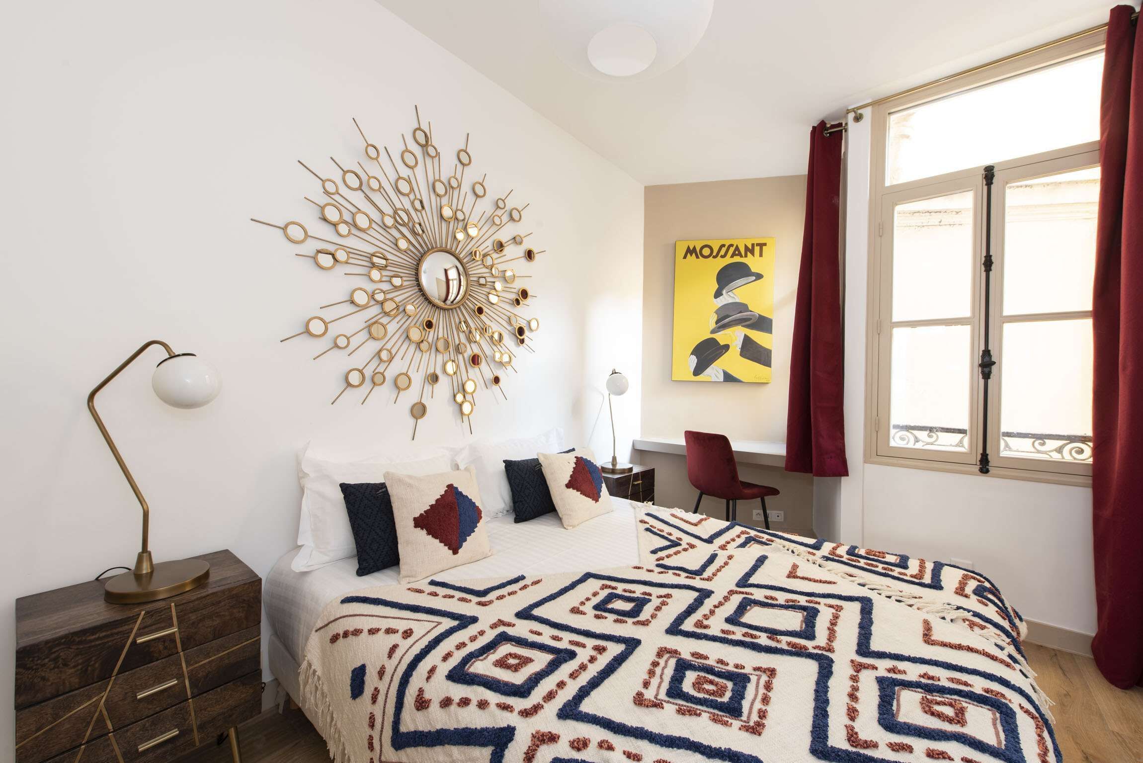 Un dormitorio con una cama, un reloj de pared, un escritorio y una ventana con cortinas.