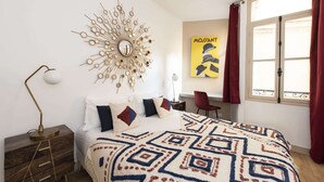 Un dormitorio con una cama, un reloj de pared, un escritorio y una ventana con cortinas.