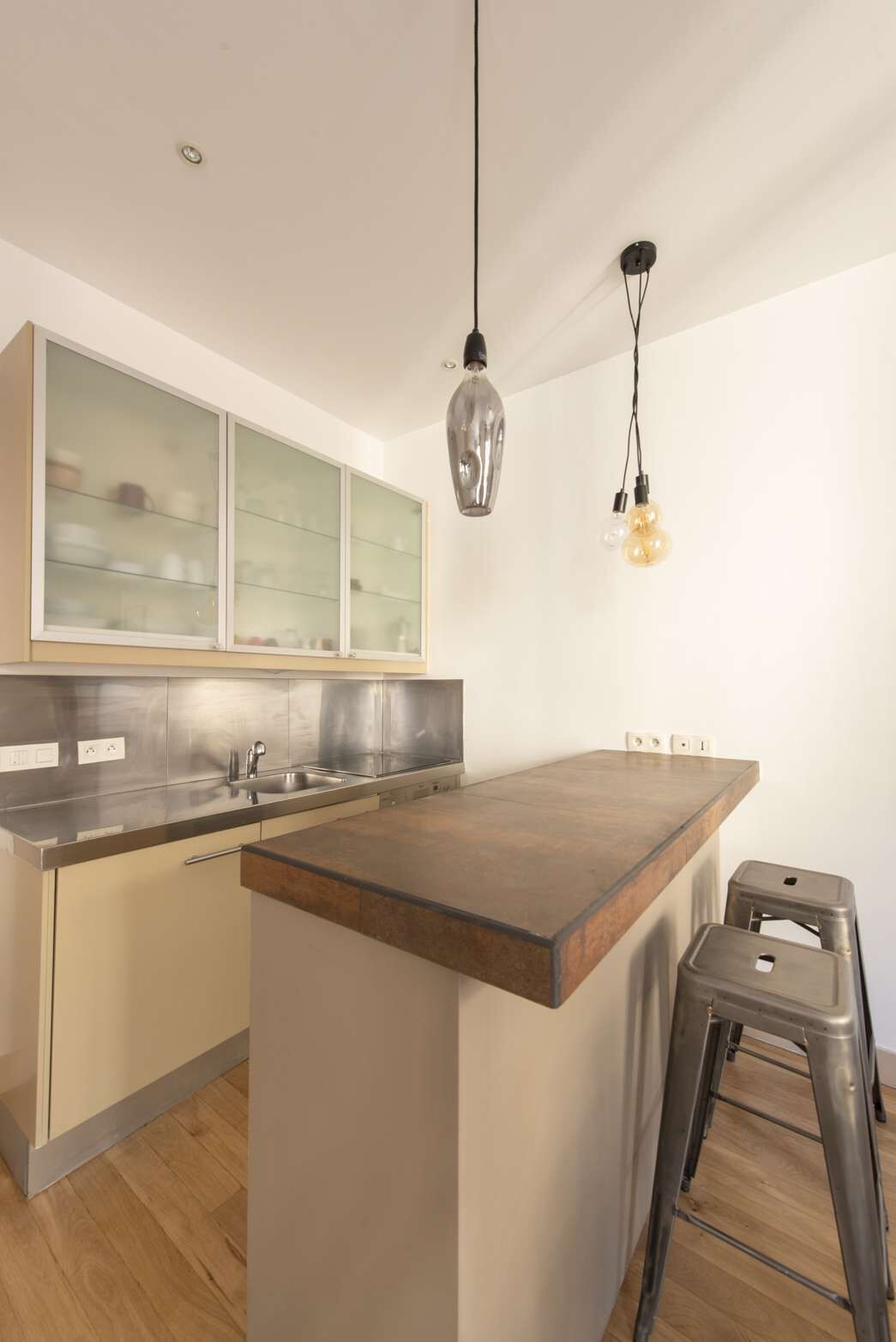 Eine moderne Küche mit einer zentralen Kochinsel, Edelstahlgeräten und einem Glaskabinet.