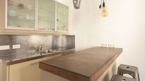 Cocina moderna con una isla central, electrodomésticos de acero inoxidable y un armario con puerta de vidrio.