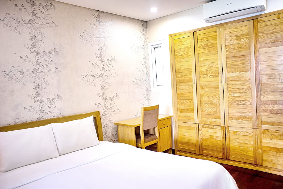 A bedroom with a bed, a desk, and a wardrobe.