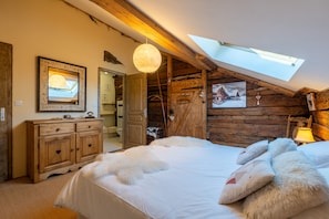 Un dormitorio acogedor con tragaluz, paredes de madera, una cama con almohadas mullidas y un aparador de madera.