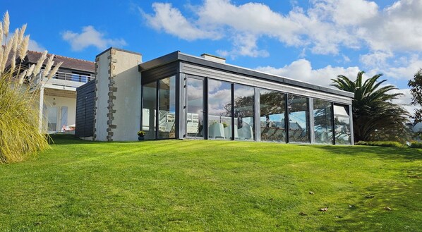 A modern building with large glass windows, a stone facade, and a well-maintained lawn.