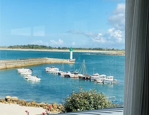 A harbor with boats docked, a lighthouse, and a view of the coastline.