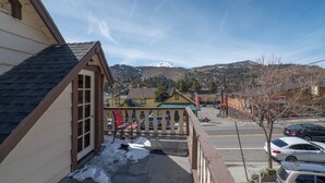 Un balcón con vistas a una montaña nevada, un estacionamiento y un edificio de fachada amarilla.