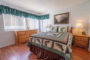 Cozy bedroom with a large bed, two bedside tables, and a dresser, featuring a beautiful painting above.