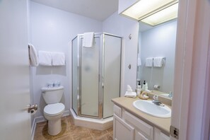 Enjoy a refreshing shower in this bathroom with a glass-enclosed shower, white toilet, and sink with a mirror.